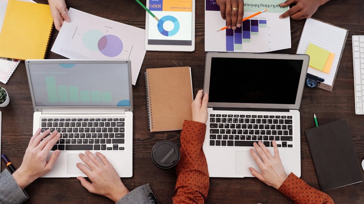 Overhead view of a team discussing digital marketing strategies with laptops and charts.