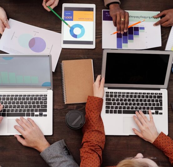 Overhead view of a team discussing digital marketing strategies with laptops and charts.
