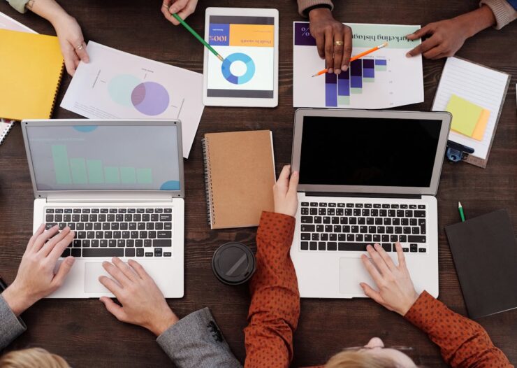 Overhead view of a team discussing digital marketing strategies with laptops and charts.